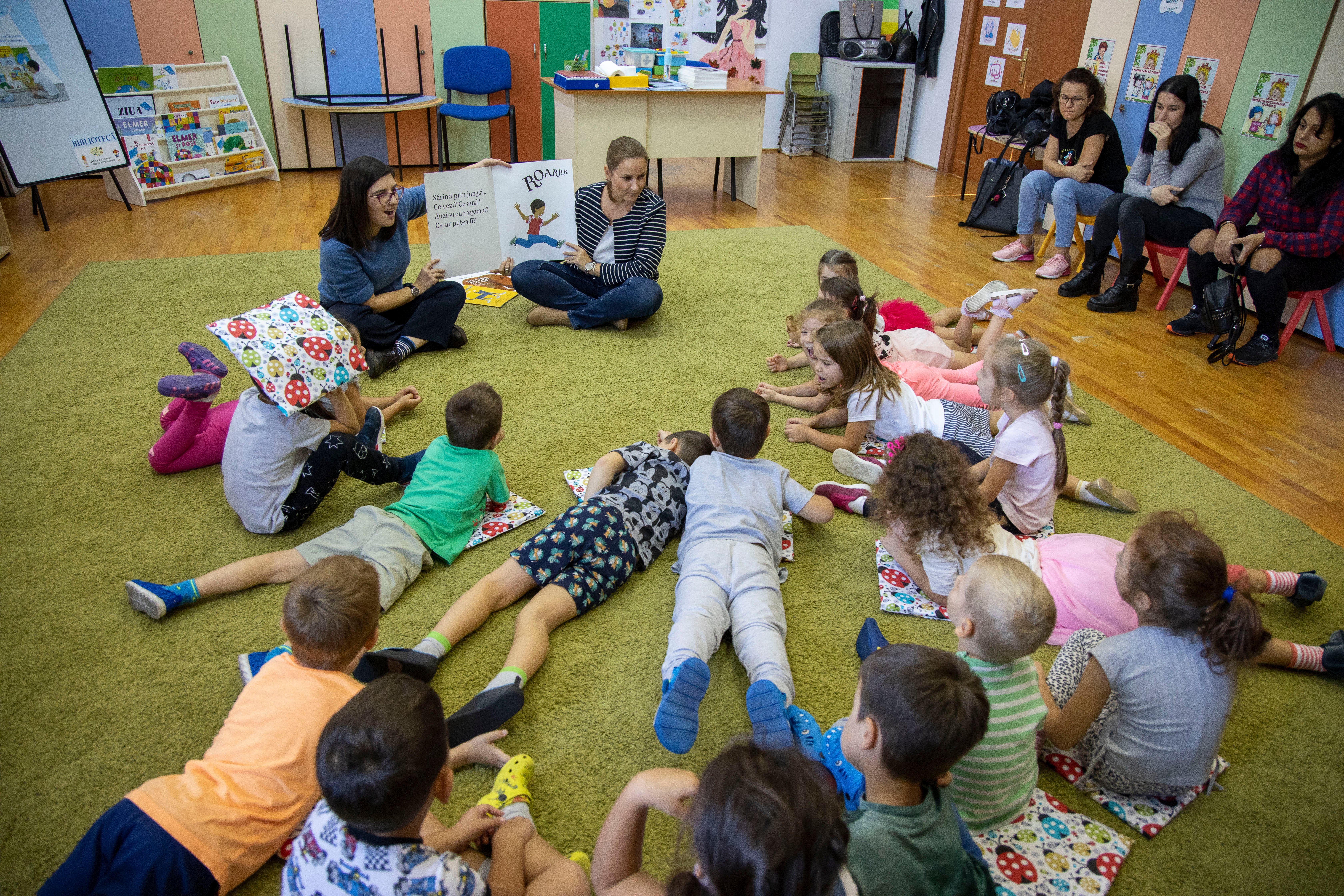 Volunteers reading to kindergarten children from marginalized areas of Bucharest
